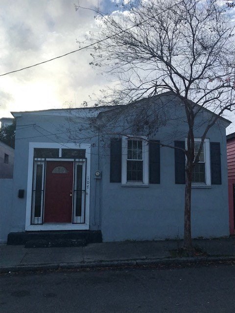 A small house with a red door and a tree in front.