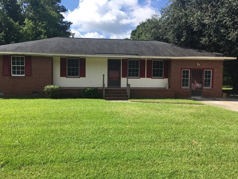 a red brick house with a lawn in front of it