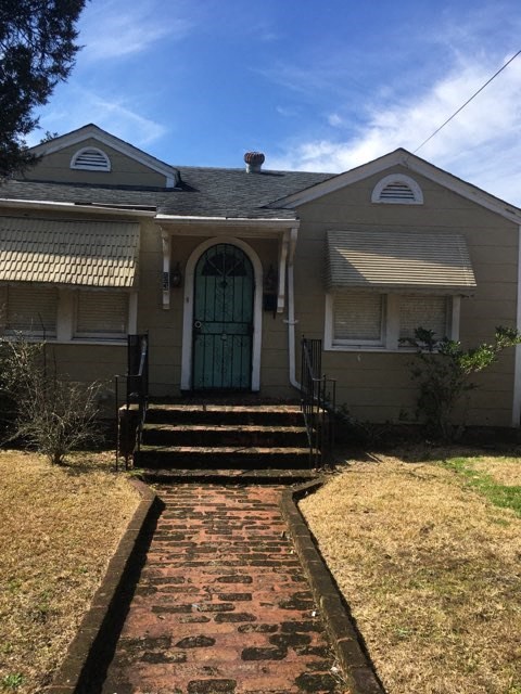 A house with a green door and a brick pathway leading to it.