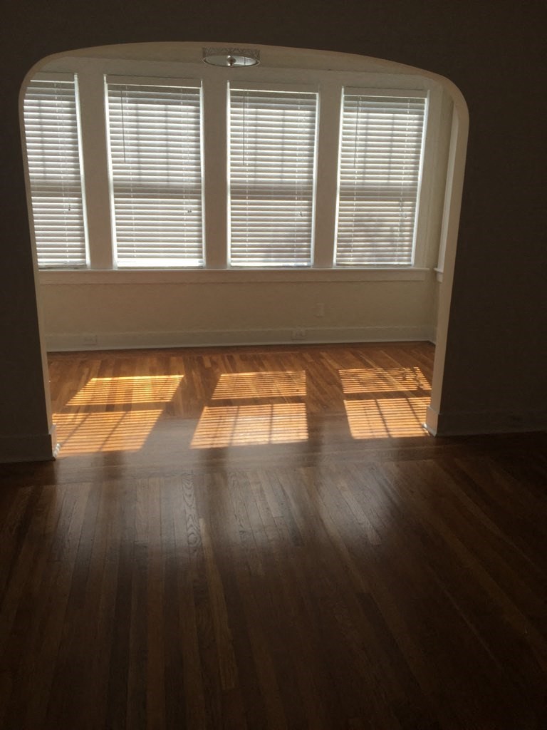 A room with wooden floors and a window with blinds.