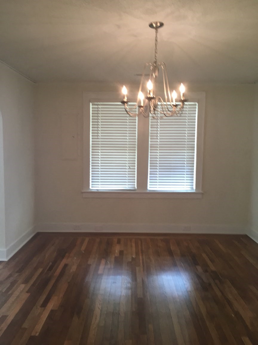 A room with a chandelier and a window with blinds.