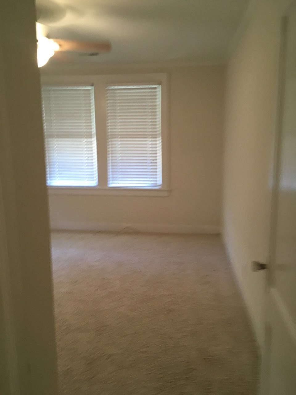 A room with a carpeted floor and a window with blinds.
