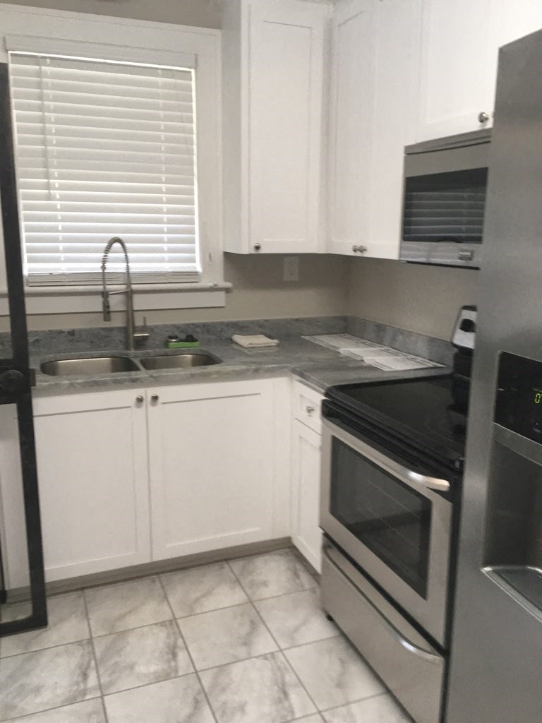 A kitchen with a black refrigerator and white cabinets.