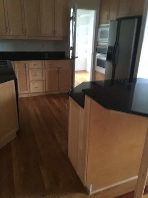 A kitchen with wooden cabinets and black countertops.