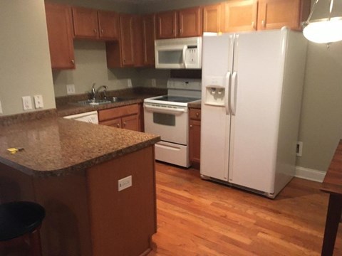 A kitchen with a white refrigerator and brown cabinets.