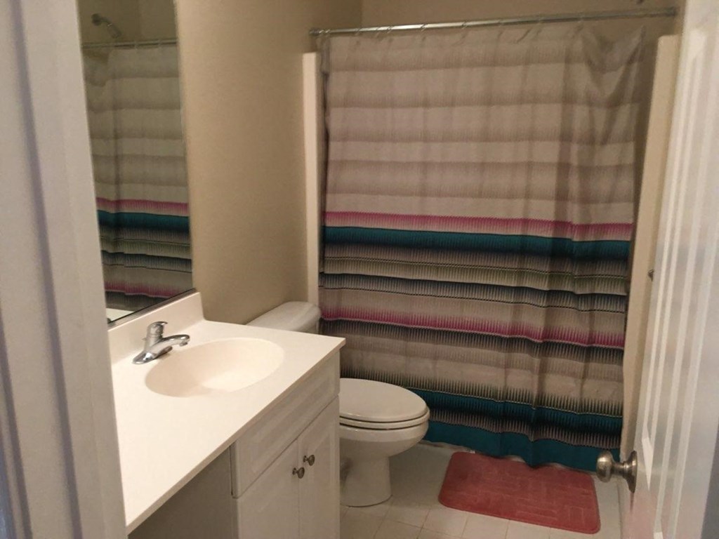 A bathroom with a white sink, toilet, and a shower curtain.