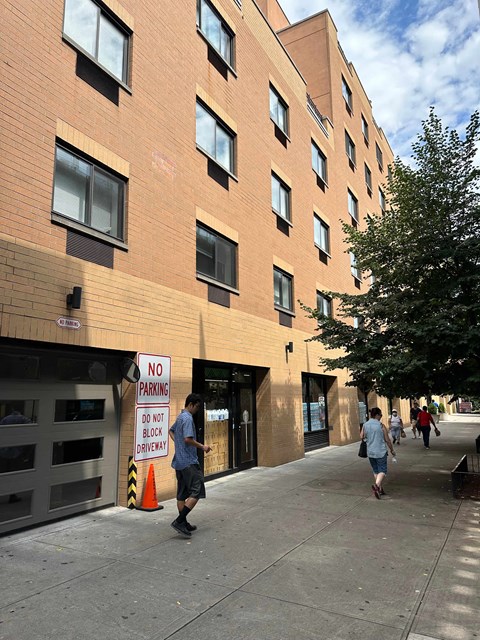 people walking past a building with a no parking sign