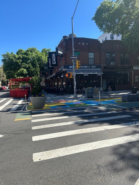 A street view with a crosswalk and a building with a sign that says "Kitchen & Bar".