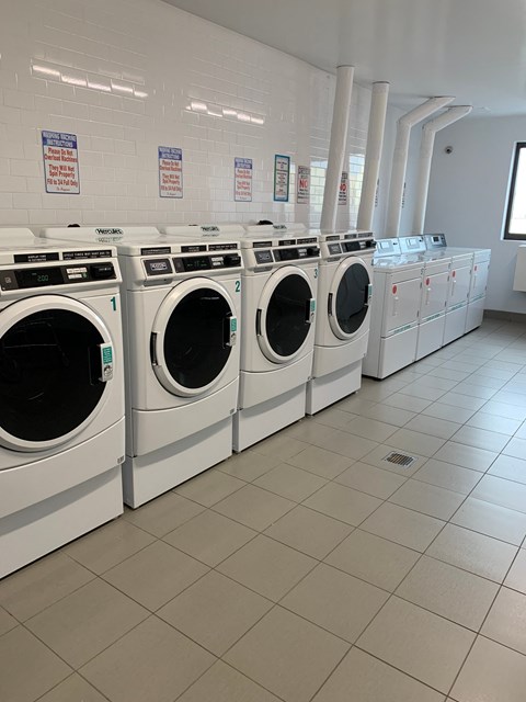a row of washers and dryers in a laundry room