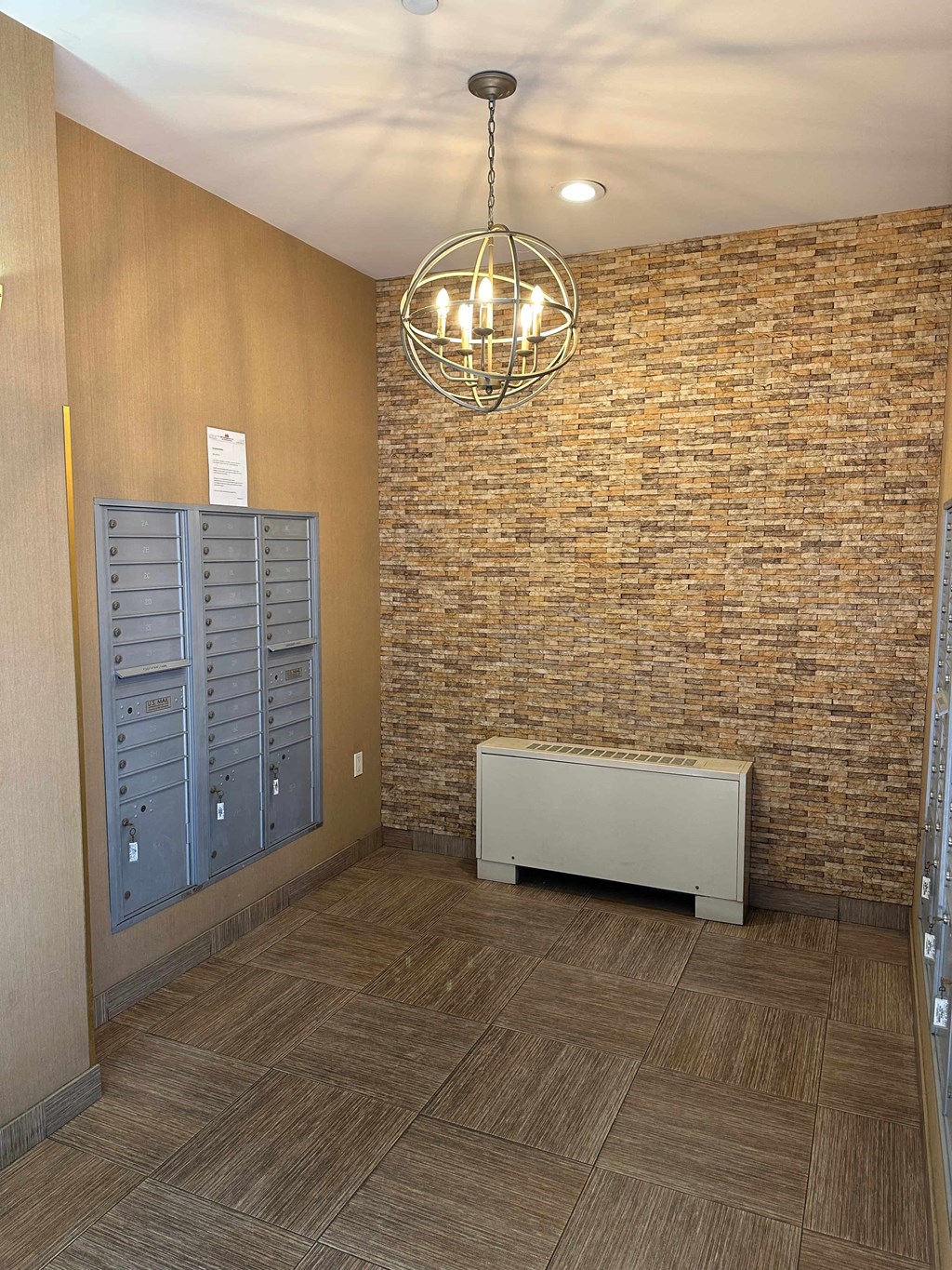 a hallway with a brick wall and lockers and a chandelier