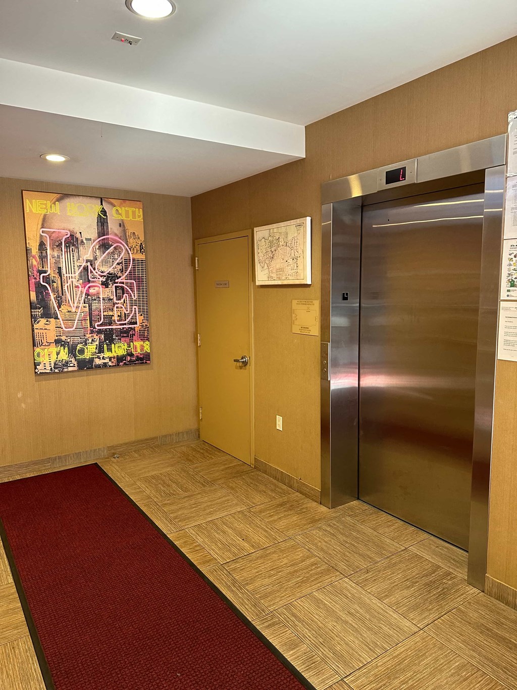 a lobby with a metal elevator and a painting on the wall