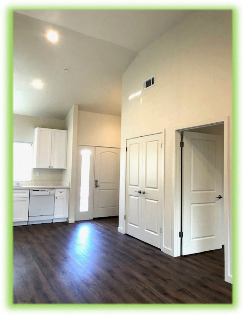 an empty kitchen with white cabinets and a wooden floor