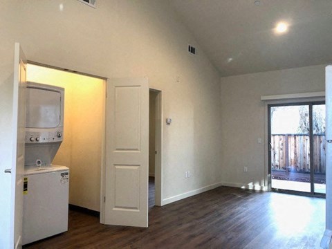 an empty living room with a refrigerator and a door