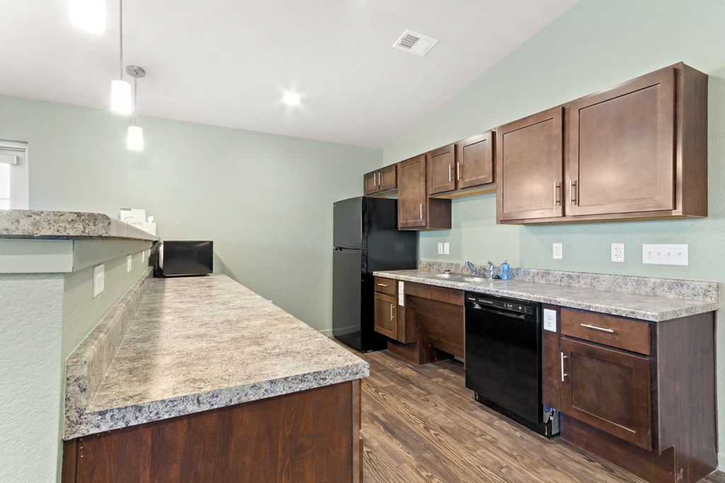 a kitchen with wooden cabinets and granite counter tops and a black refrigerator