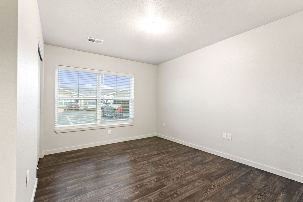 an empty living room with wood flooring and a window