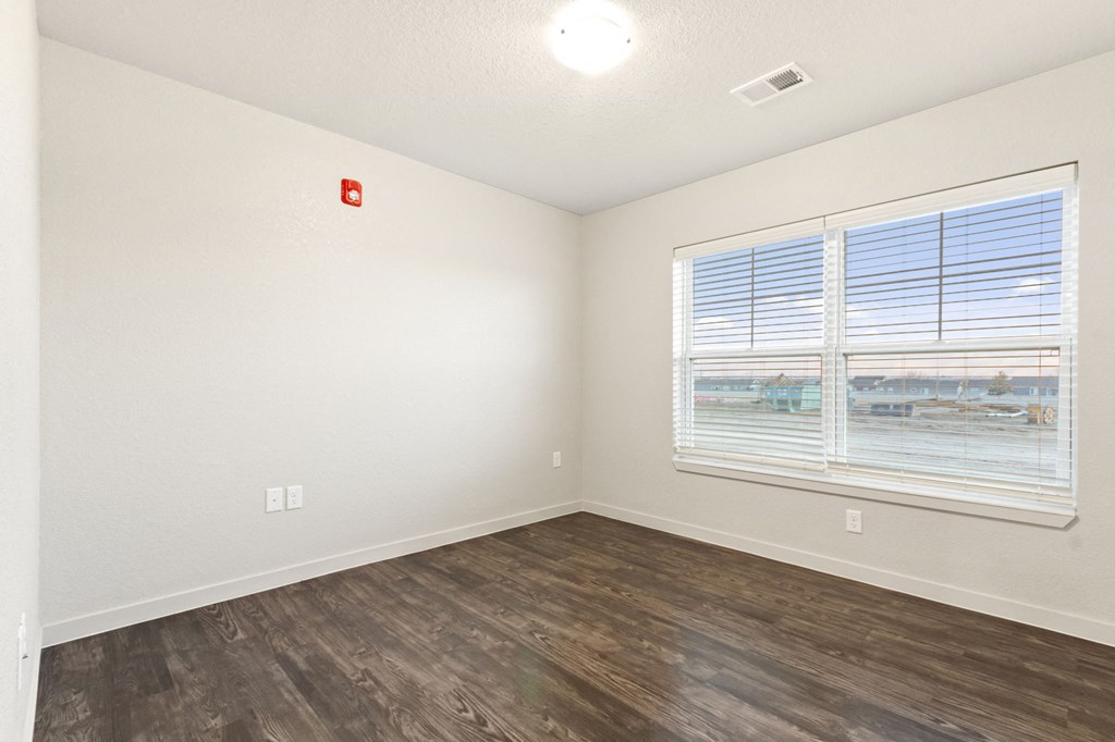 an empty living room with a window and wood flooring