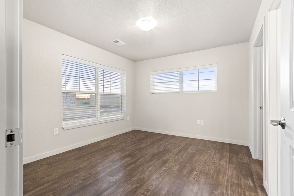 an empty living room with wood flooring and a window