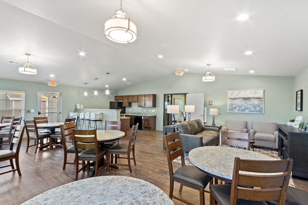 a large living room with tables and chairs and a kitchen