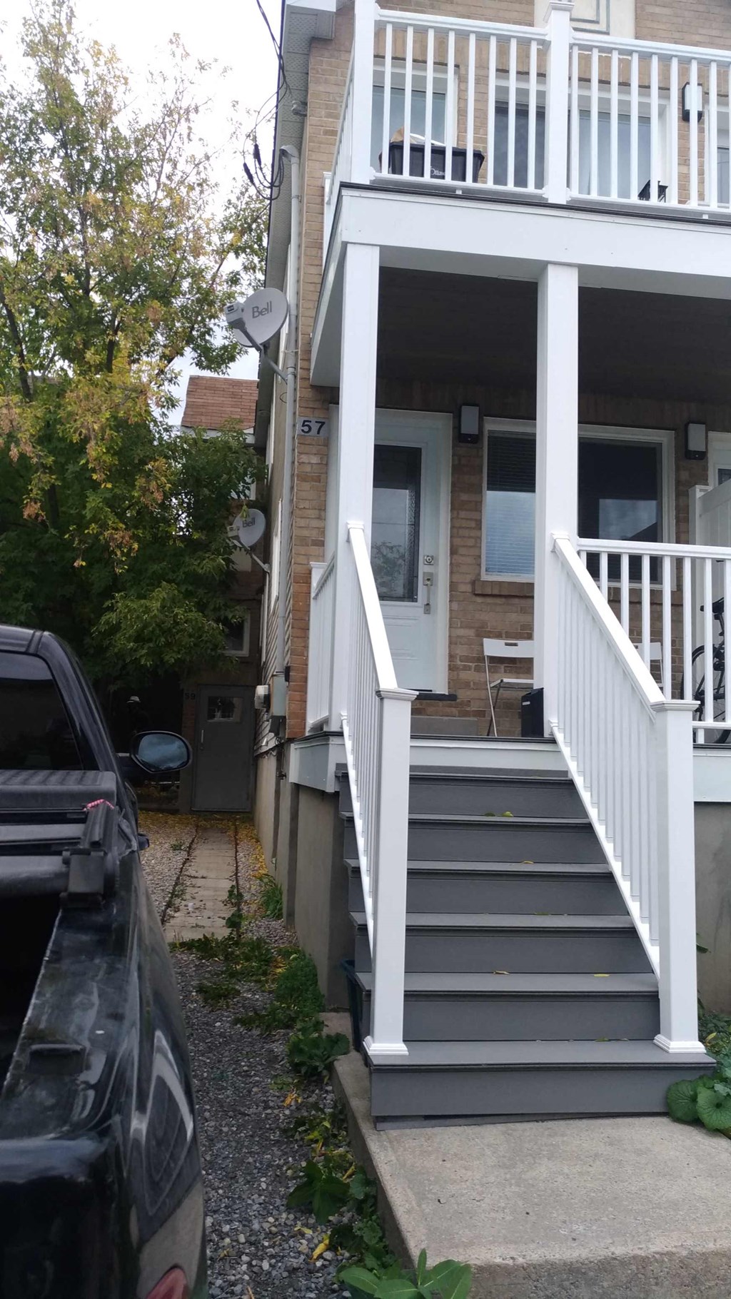 the front steps of a house with a car parked in front