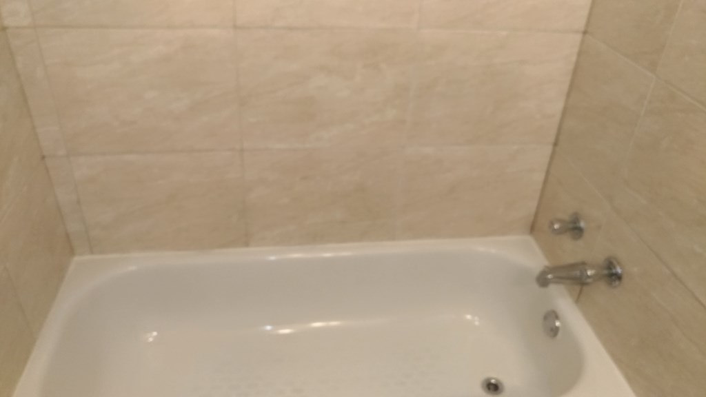 a white bath tub in a bathroom with white tiles