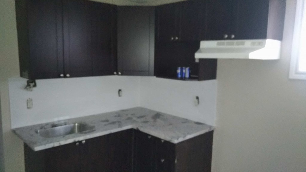 an empty kitchen with white walls and black cabinets