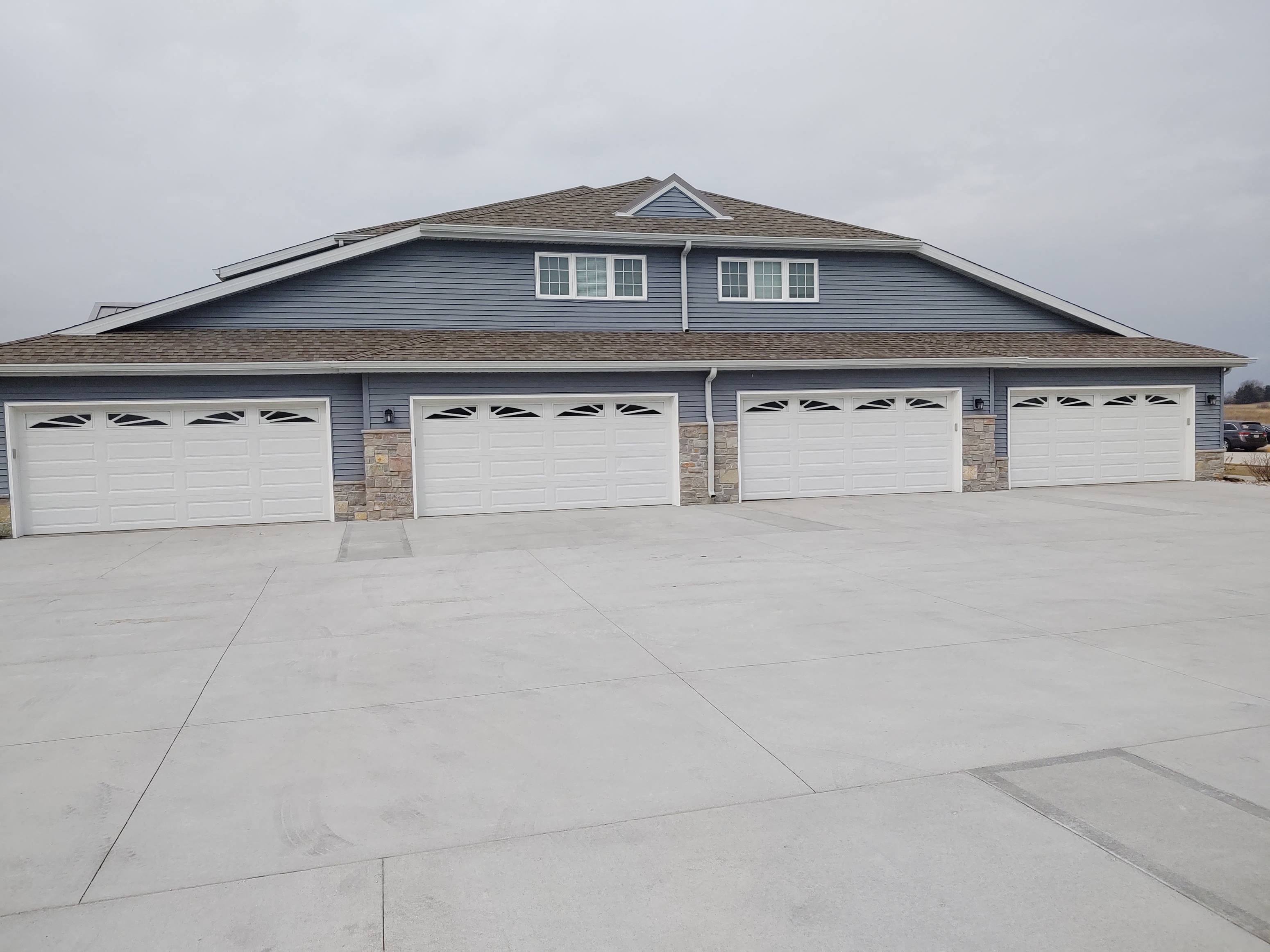a row of white garage doors in front of a house