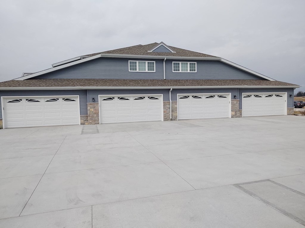 a row of white garage doors in front of a house