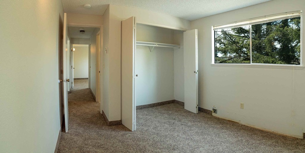 an empty bedroom with a large window and a closet