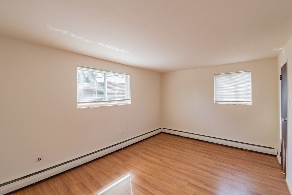 the spacious living room with hardwood flooring and two windows