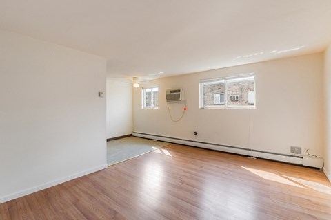 the living room of an empty house with wood floors and a window