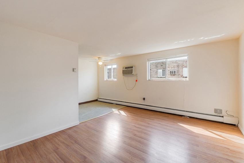 the living room of an empty house with wood floors and a window