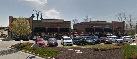 A parking lot in front of a store with cars parked.