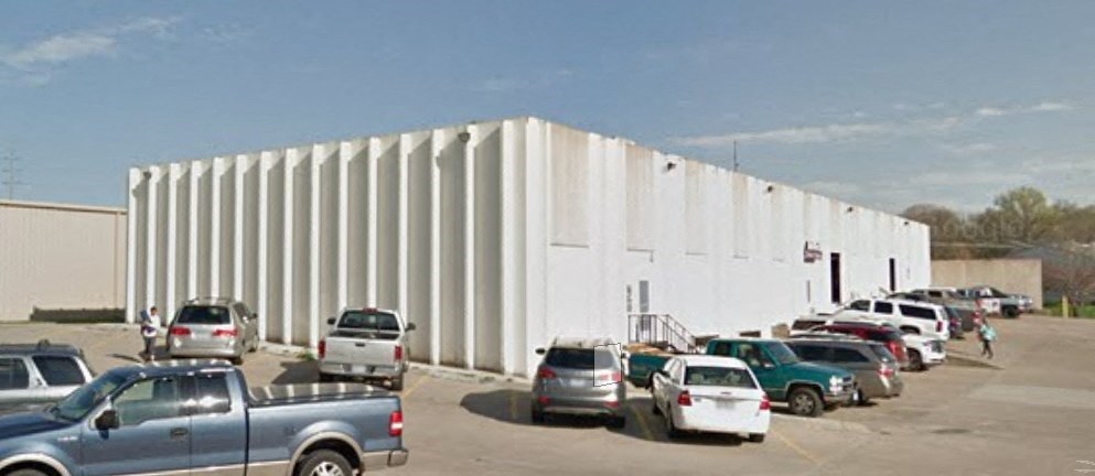 a large white building with a parking lot full of cars