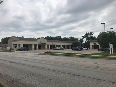 A cloudy day at a parking lot with a building in the background.