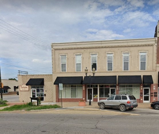 A car is parked in front of a building with a black awning.