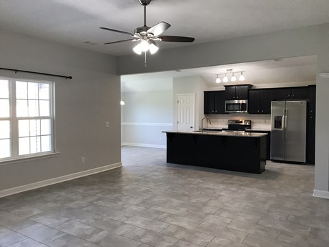 an empty kitchen and living room with a ceiling fan
