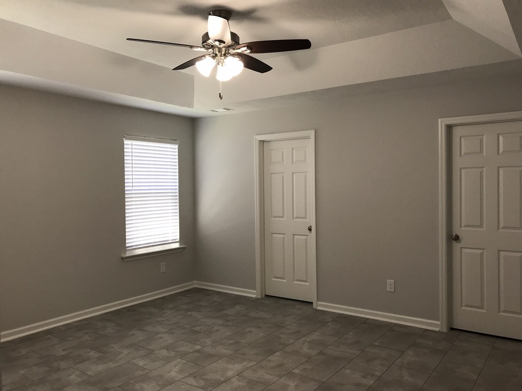 a living room with a ceiling fan and two doors