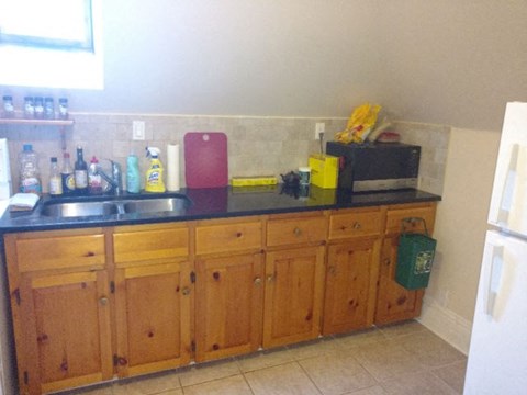 A kitchen with wooden cabinets and a black counter top.