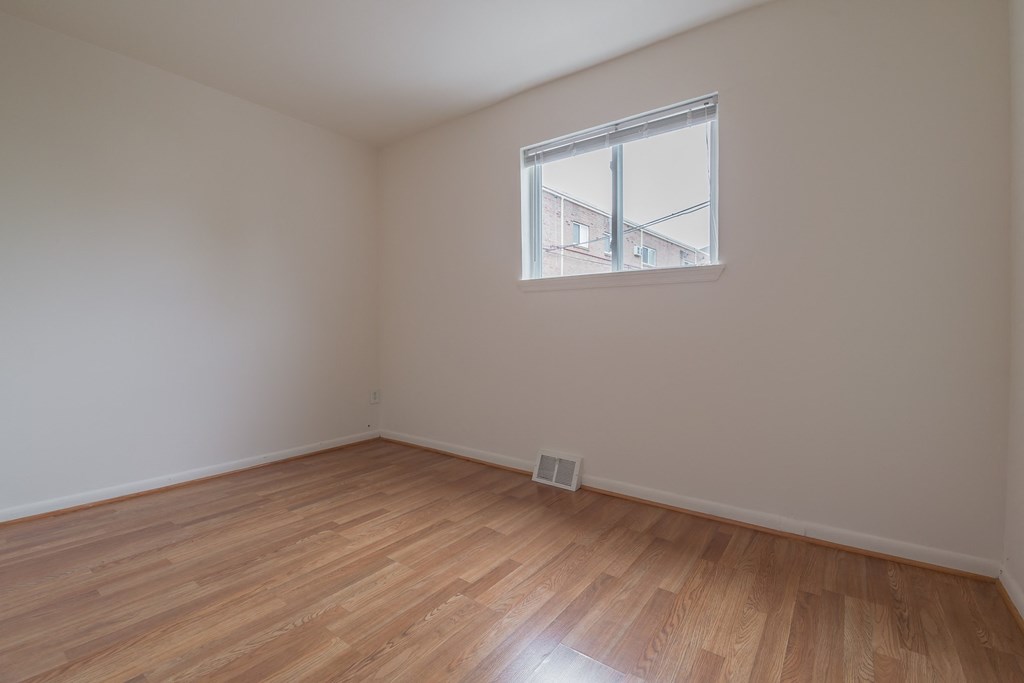 an empty room with wood floors and a window