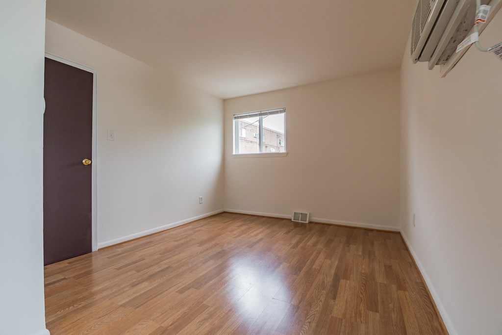 an empty living room with wood floors and a window