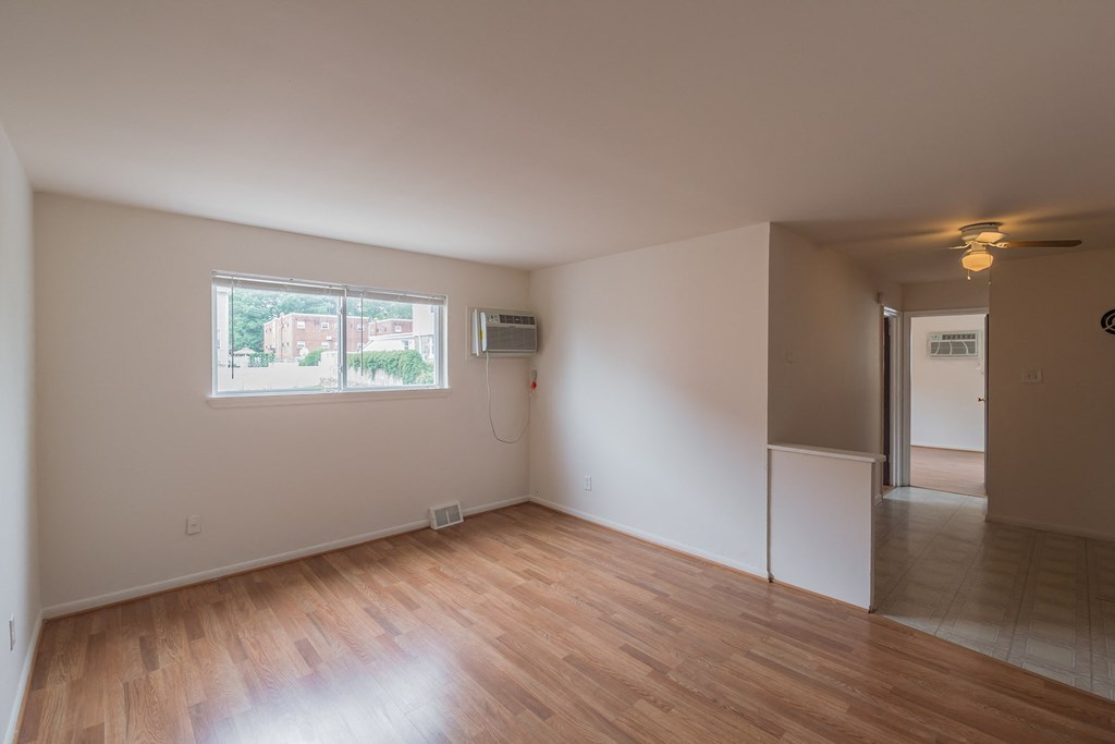 an empty living room with wood floors and a window