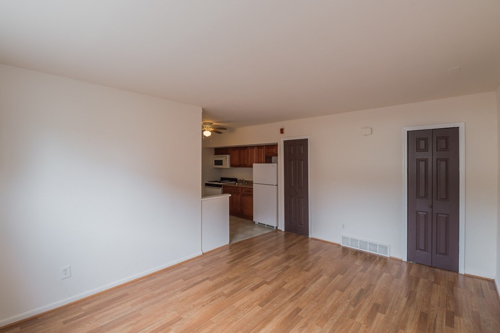 the living room and kitchen of an empty apartment with wood flooring