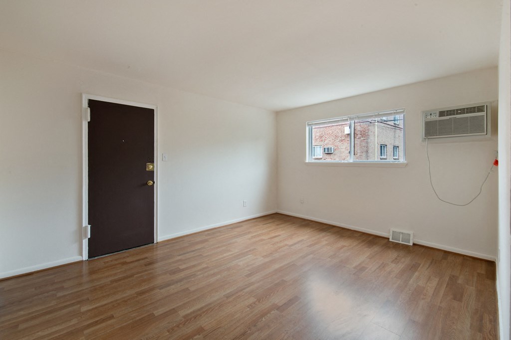 an empty living room with wood floors and a window