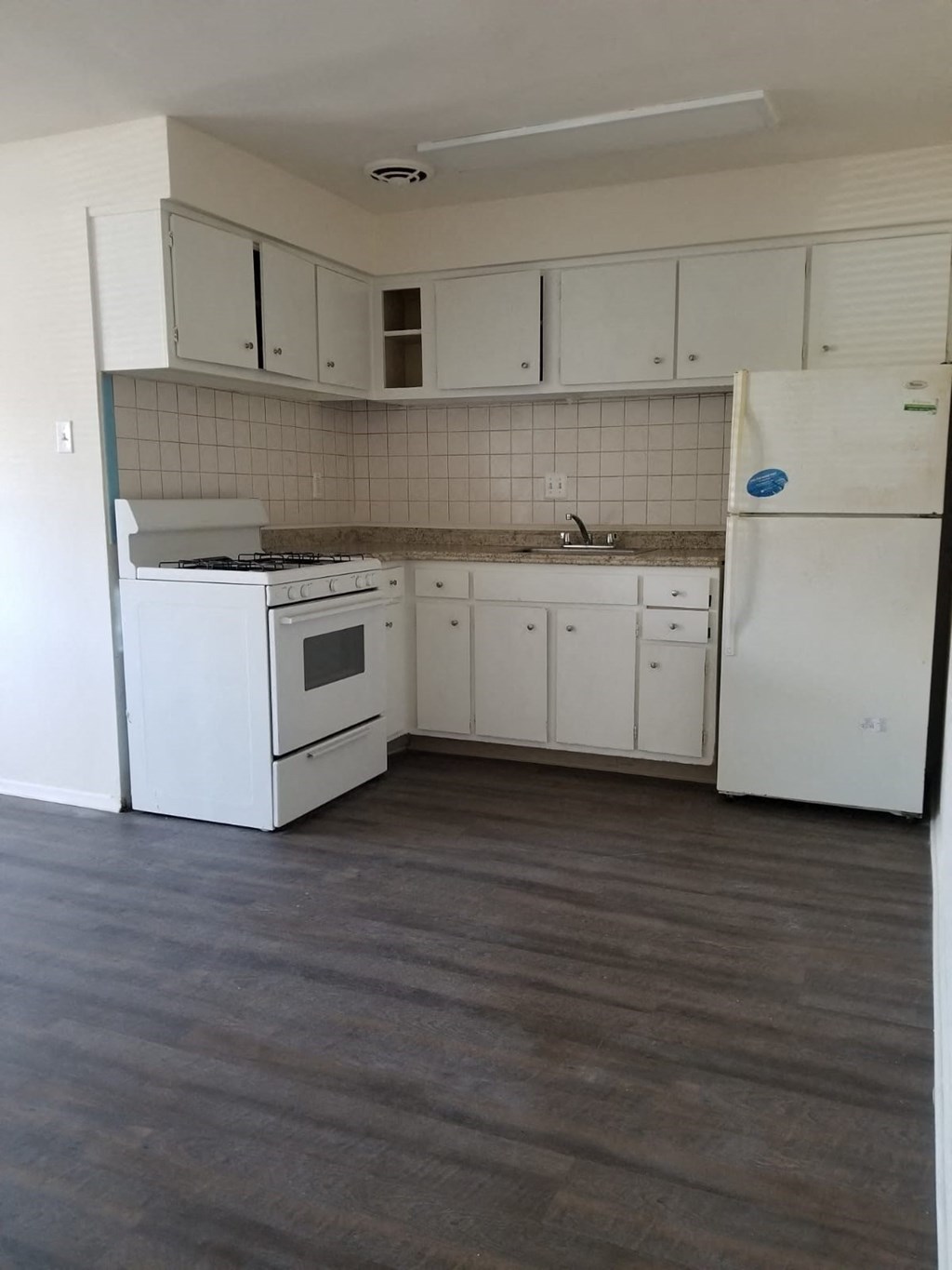 an empty kitchen with white appliances and white cabinets