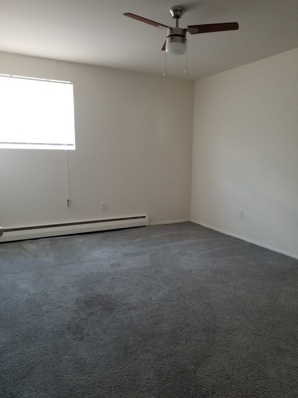 an empty room with a ceiling fan and a window