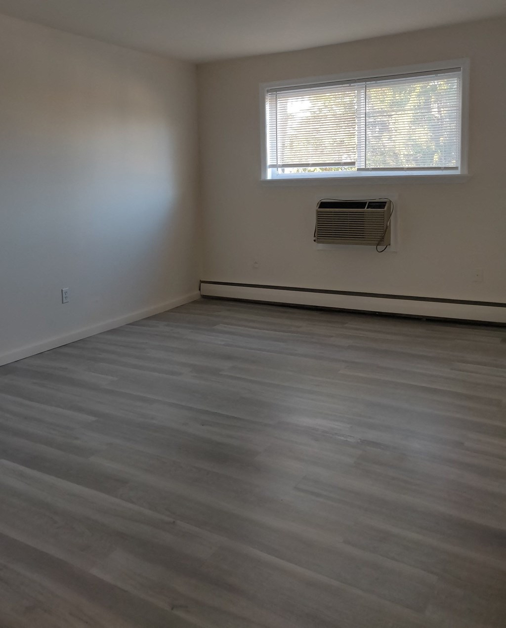 an empty room with wooden floors and a window