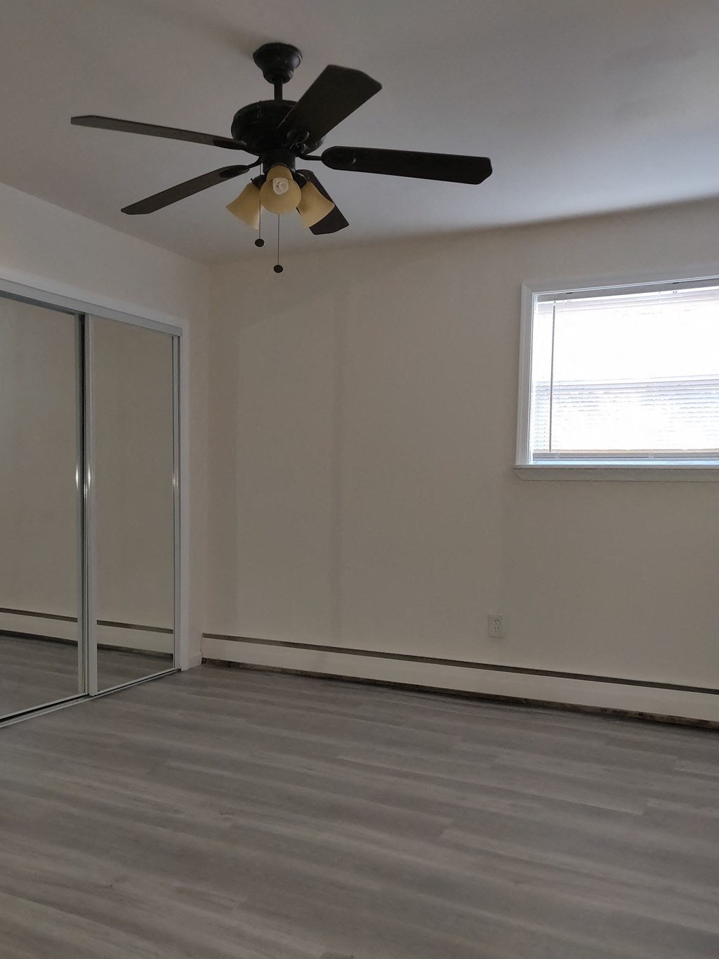 an empty room with a ceiling fan and a closet