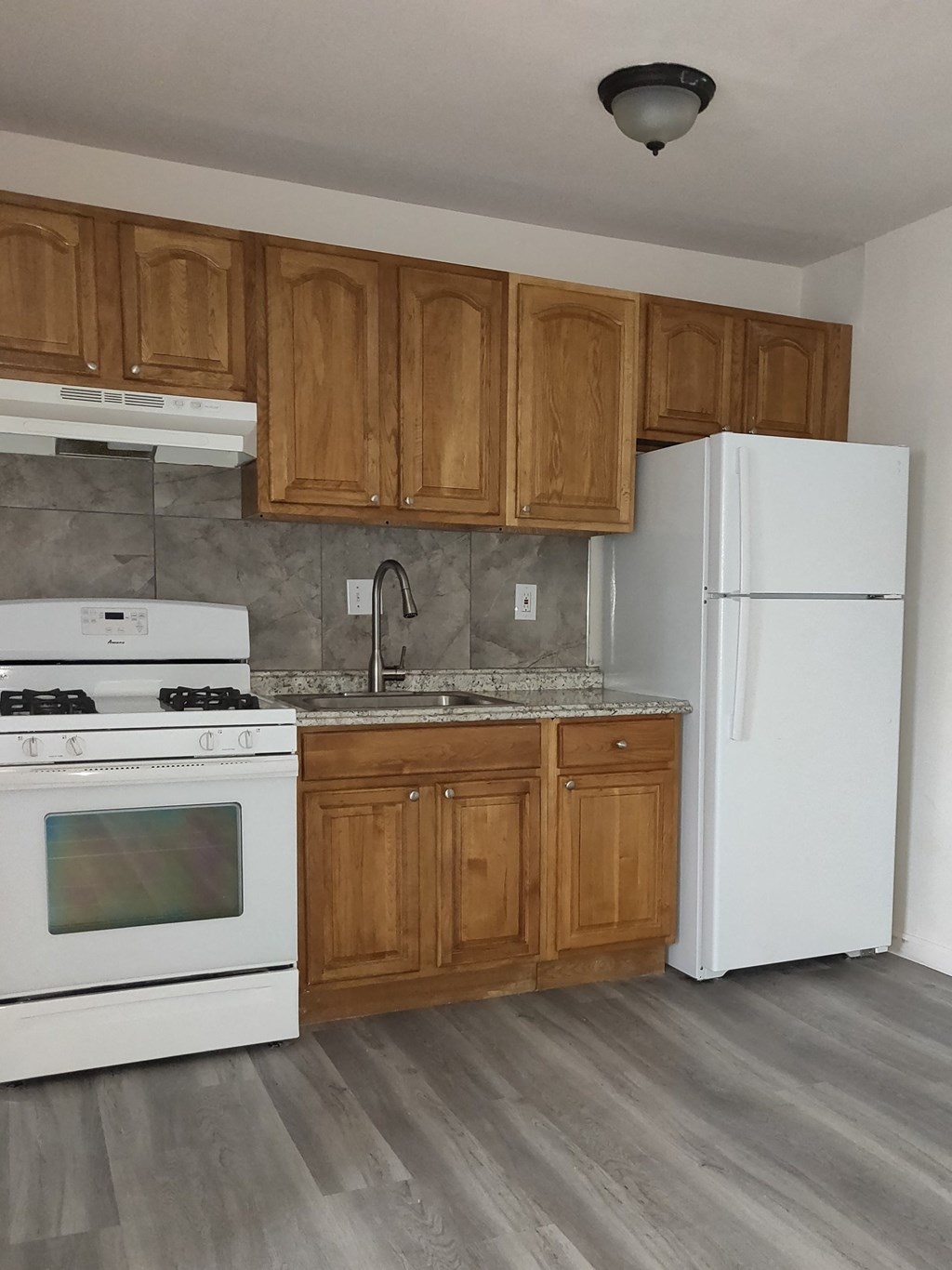 an empty kitchen with white appliances and wooden cabinets