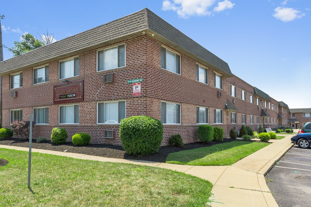 a brick apartment building with a sidewalk in front of it
