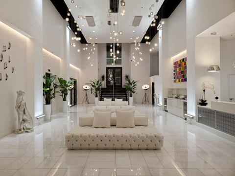 A white living room with a large white sofa and a glass staircase.